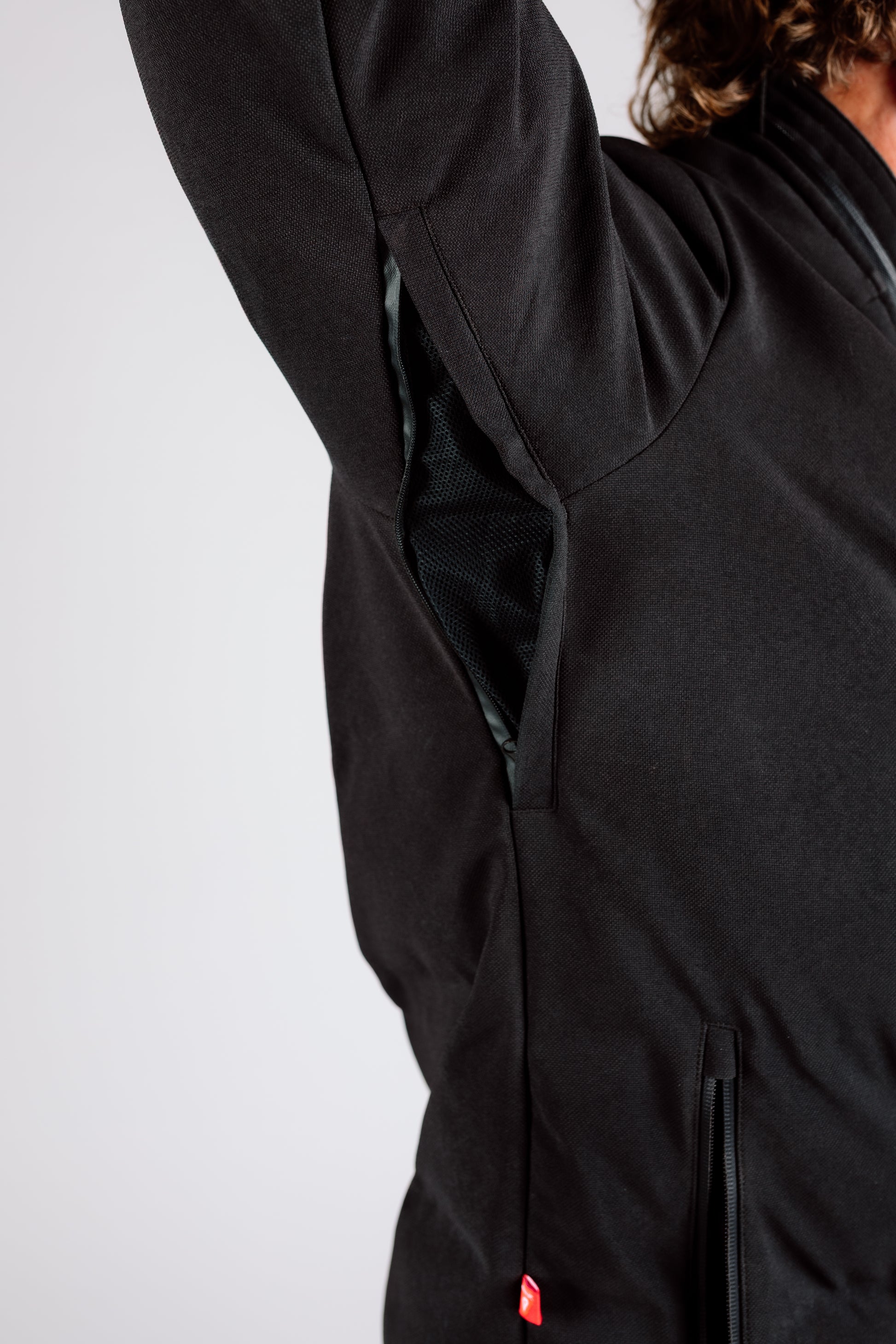 Close-up of a person wearing a black jacket with a plain background
