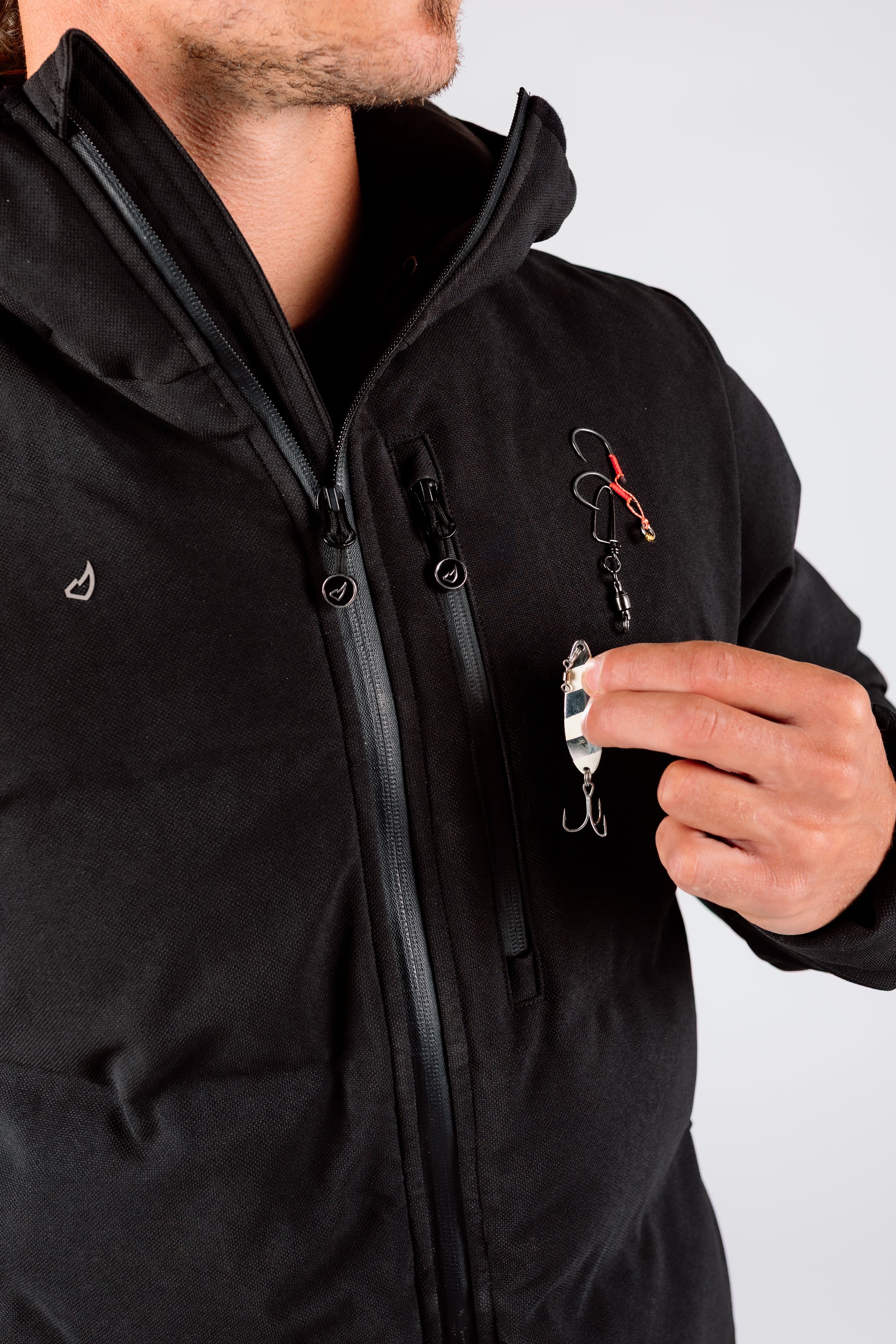 Person wearing a black jacket holding fishing equipment against a white background