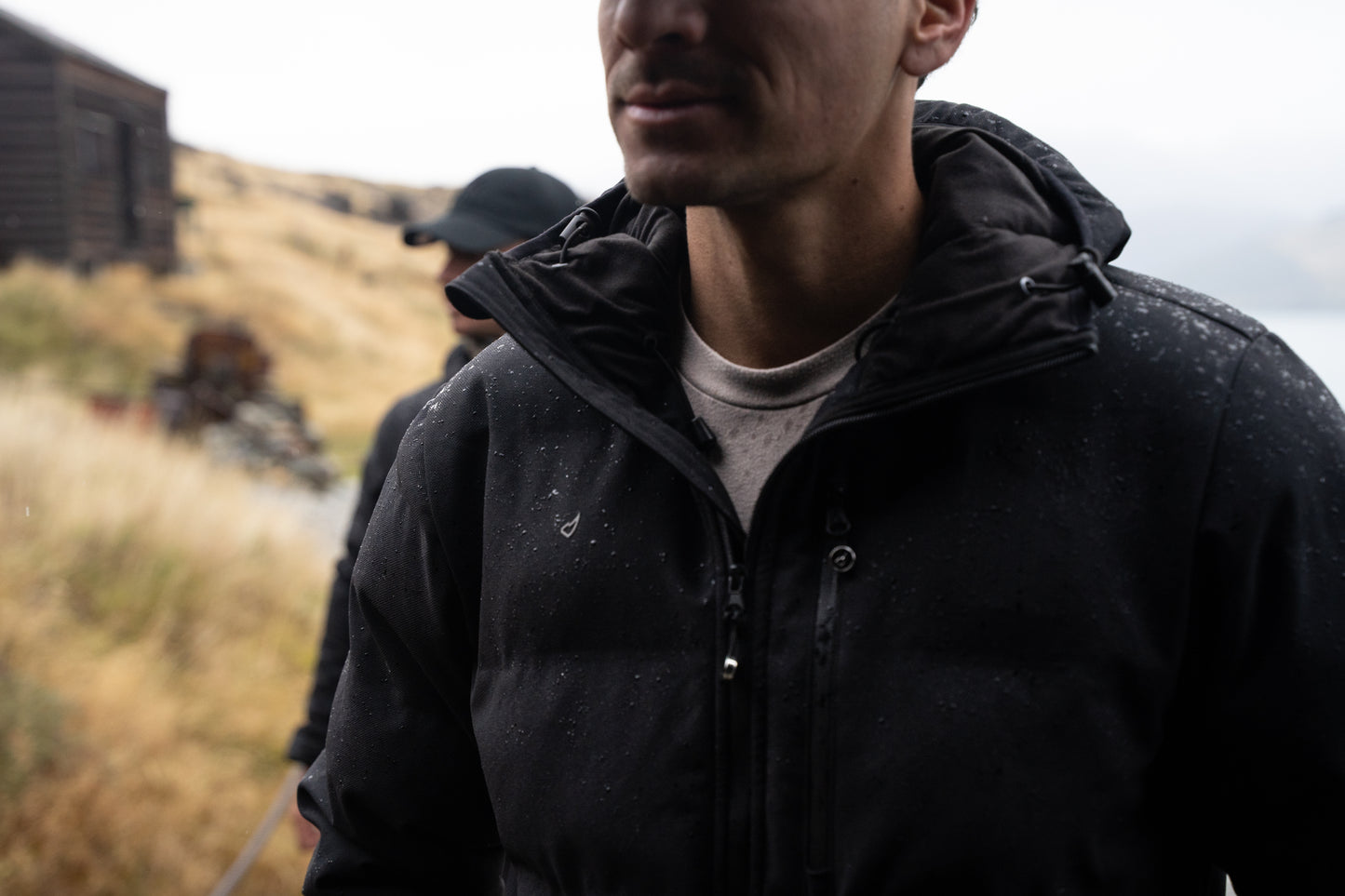 Man in a black jacket standing outdoors with a blurred background