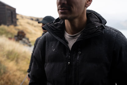 Man in a black jacket standing outdoors with a blurred background
