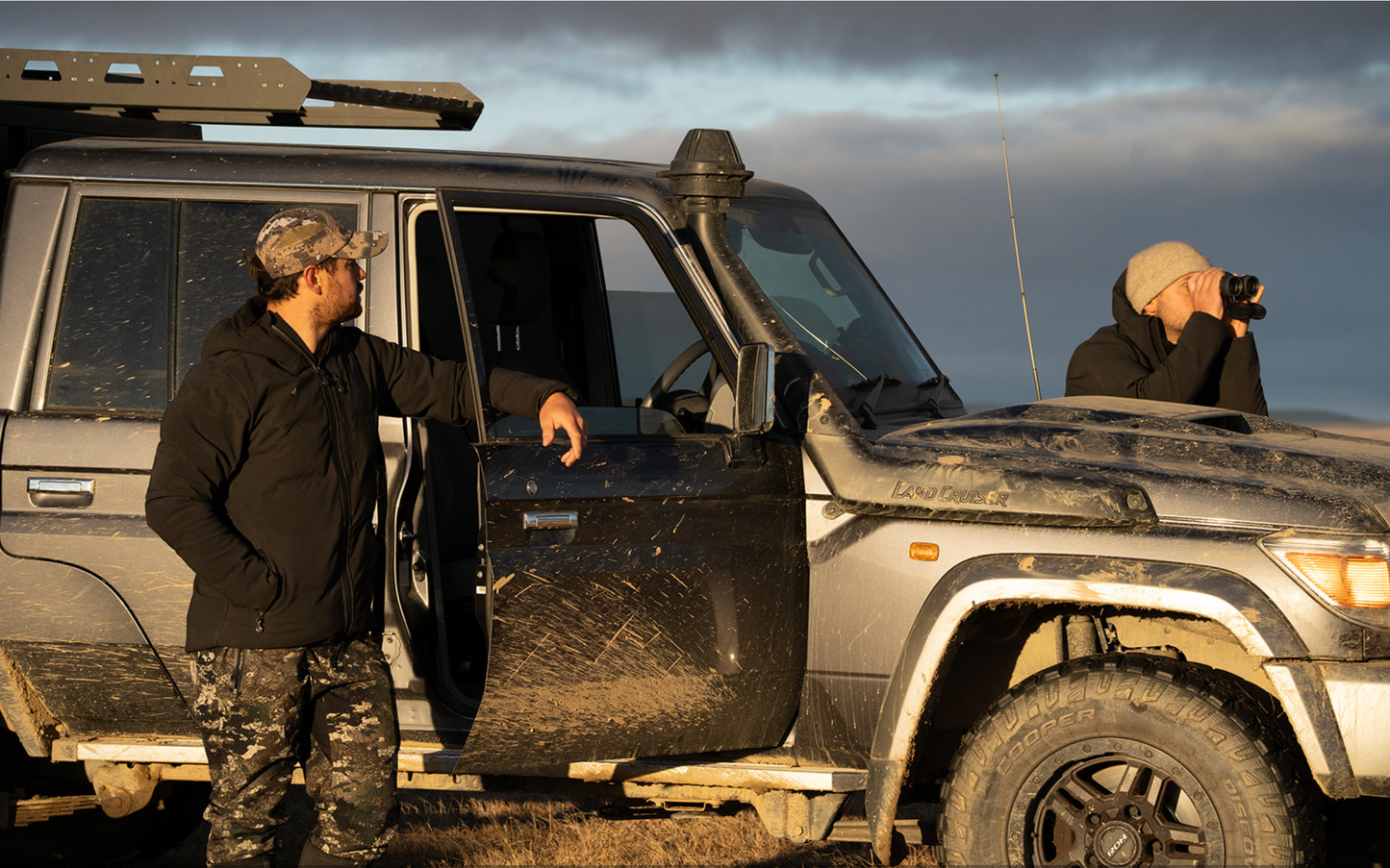 Two people by a rugged SUV in an outdoor setting